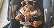 Prince joined the competition — help win amazing prizes! baby, sunglasses, pacifier, car_seat, bib, clothing, infant, child, person, seat_belt, footwear, socks, hand, face, indoor, cute, relaxing, accessory, summer, shade