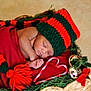 baby, sleeping, basket, blanket, knit_hat, red, green, candy_cane, heart_shape, jingle_bells, holiday, christmas, decorations, peaceful, infant, cozy, festive, wrapped, cute, portrait