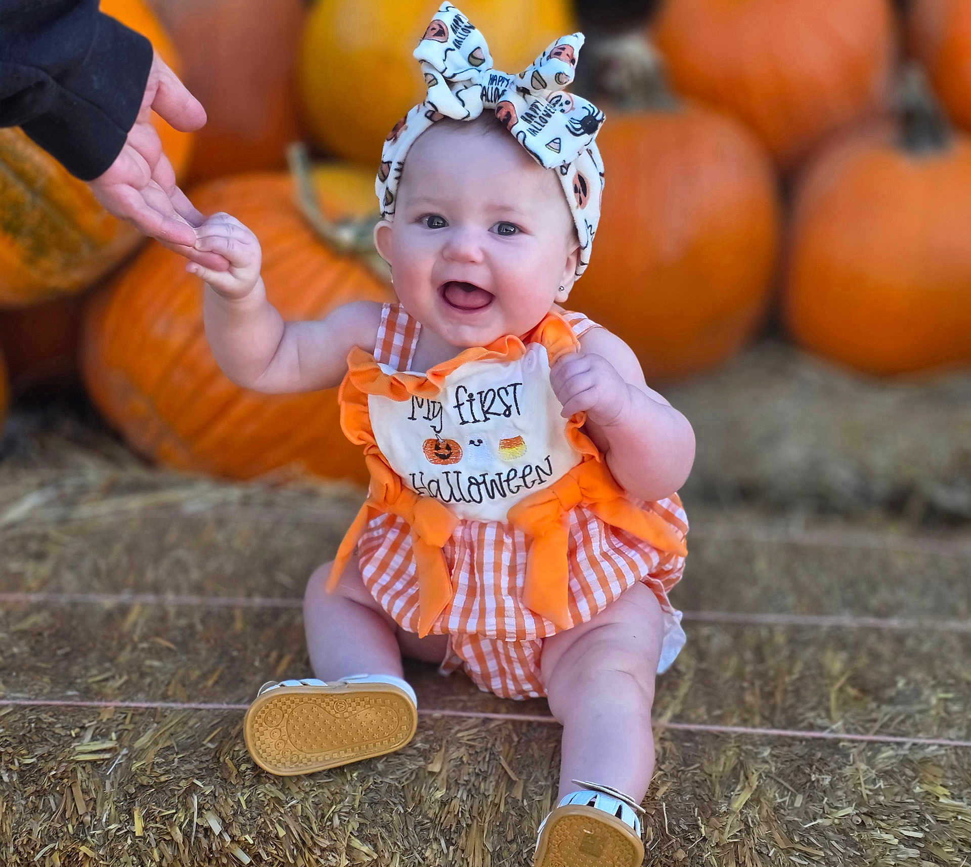 Skadi is registered to the contest to win money with this photo: autumn, baby, bow, celebration, child, cute, festive, footwear, halloween, hand, happy, hay, headband, orange, outdoor, person, pumpkin, seasonal, sitting, smiling