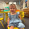 child, toddler, smiling, headband, denim, romper, yellow_chair, classroom, toys, educational_posters, carpet, bench, table, happy, indoor, person, furniture, playroom, cute, kid