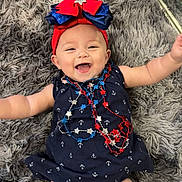 Valentina Jade. is registered to the contest to win money with this photo: anchors, baby, blue, bow, child, cute, dress, fluffy, happy, headband, indoors, infant, lying_down, navy_blue, necklaces, person, red, rug, smiling, stars