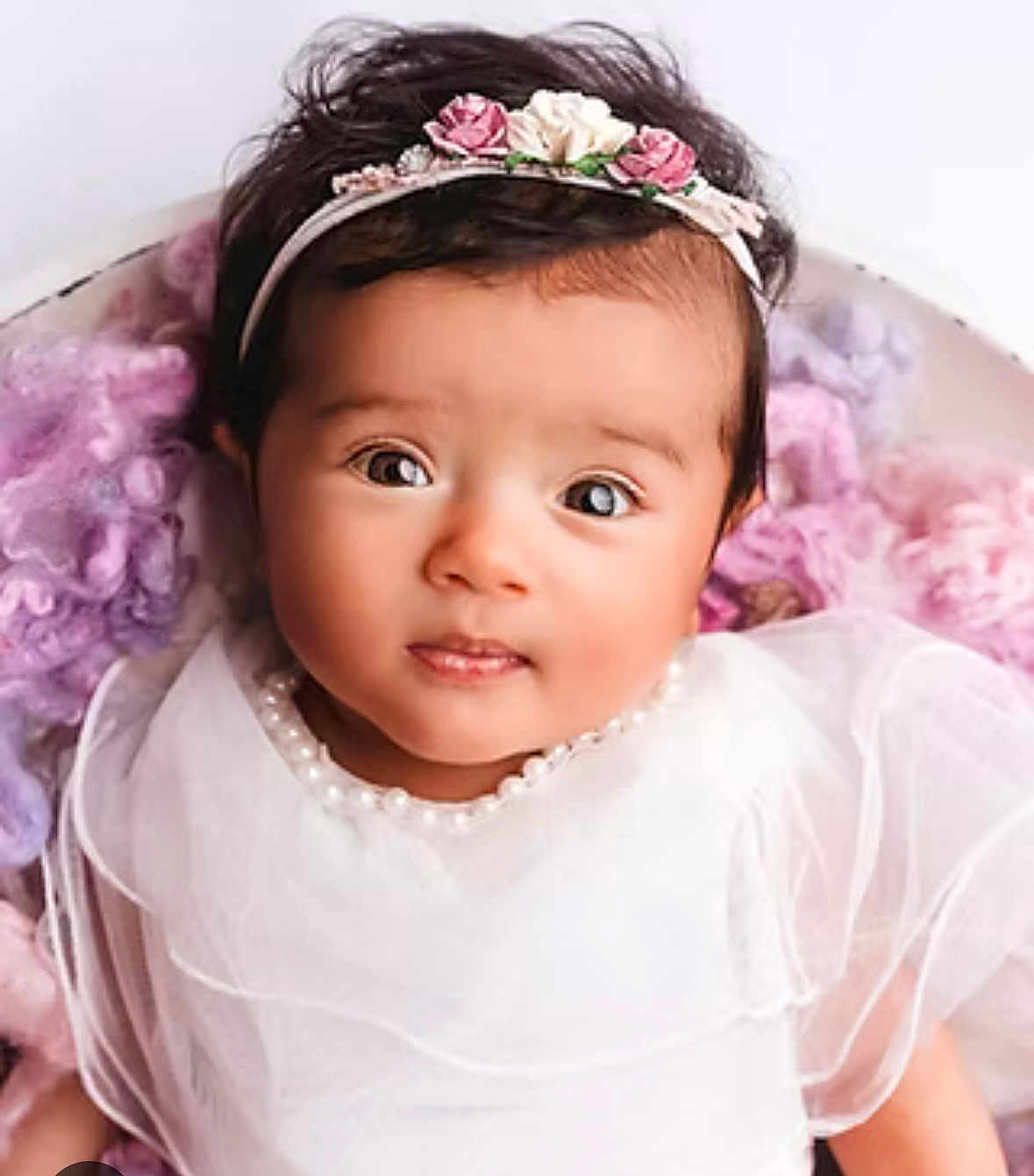 Melya a rejoint le concours — aidez-le/la à gagner de superbes lots ! baby, child, portrait, white_dress, headband, flowers, pearl_necklace, curly_hair, close_up, soft_texture, blanket, pastel_colors, cute, innocent, indoors, smiling, young_child, beautiful, adorable, person