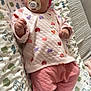 baby, infant, pacifier, headband, pink, heart_pattern, clothing, lying_down, cushion, animal_print, fabric, footwearless, cute, indoors, sleepwear, child, soft_toys, blanket, relaxing, portrait
