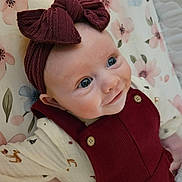 Wren joined the competition — help win amazing prizes! baby, infant, smiling, face, headband, bow, blue_eyes, clothing, overalls, floral_pattern, blanket, cute, lying_down, soft_lighting, indoor, child, happy, portrait, closeup, person