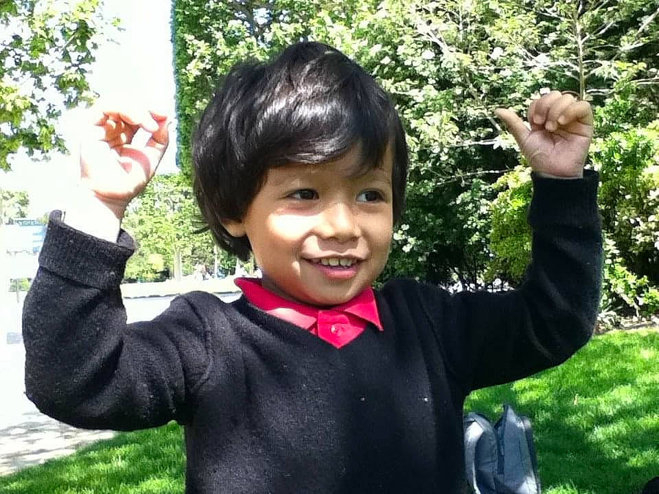 Tiago participe au concours pour gagner de l'argent avec cette photo : child, event, finger, formal_wear, fun, gesture, grass, happy, joy, leisure, outerwear, people_in_nature, person, plant, recreation, sleeve, smile, suit, terrestrial_plant, thumb