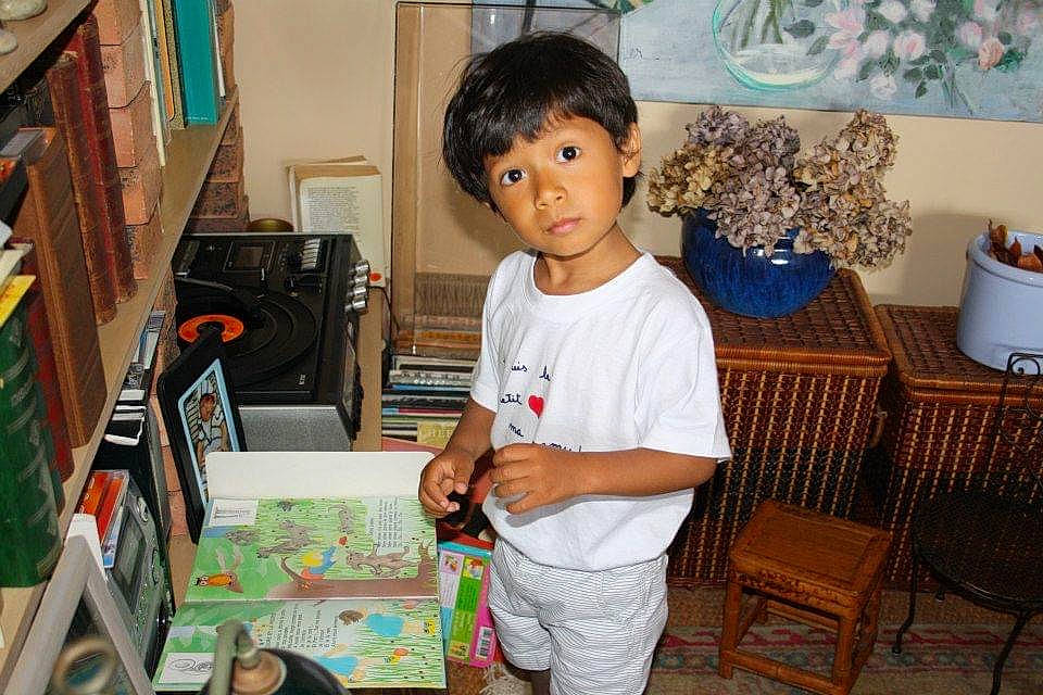 Tiago participe au concours pour gagner de l'argent avec cette photo : audio_equipment, bookcase, box, chair, child, electronic_device, event, fun, happy, holiday, leisure, person, picture_frame, play, room, shelf, standing, t_shirt, visual_arts, wood