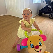 Camila is registered to the contest to win money with this photo: baby, bright, child, colorful, cute, door, floor, flooring, happy, headband, indoor, person, playful, smile, standing, stroller, toy, walker, window, yellow_dress