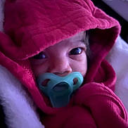 Adaijah is registered to the contest to win money with this photo: baby, pacifier, red_hood, blanket, close_up, infant, face, eyes, cozy, warm_clothing, newborn, child, portrait, cute, indoors, soft_texture, sleepwear, head_covering, small_person, snuggled