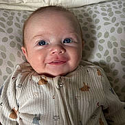 Malo participe au concours pour gagner de l'argent avec cette photo : baby, infant, blue_eyes, smile, onesie, animal_print, cushion, leaf_pattern, soft_fabric, portrait, close_up, happy, child, cute, lying_down, indoor, cozy, skin, head, face