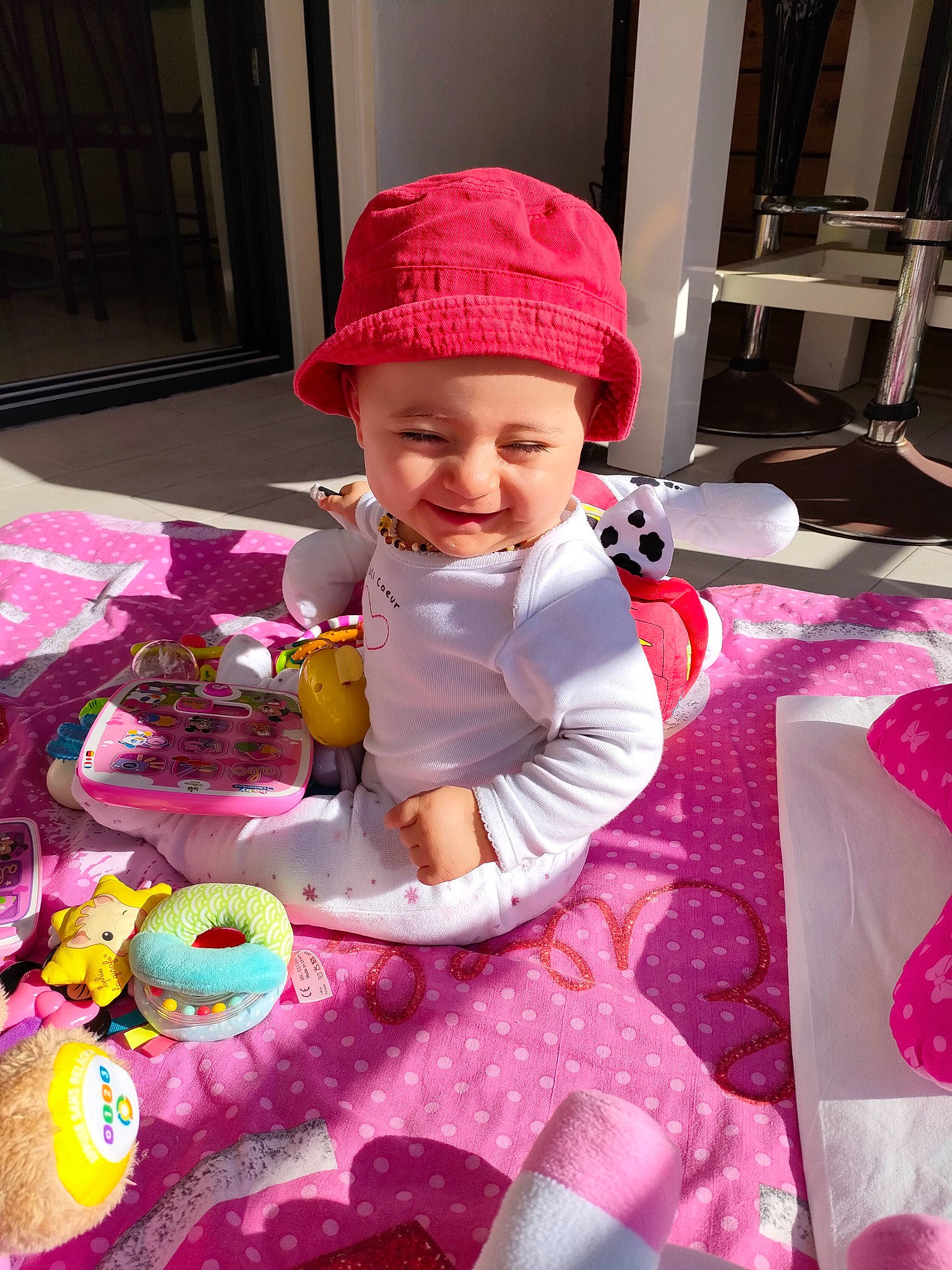 Léane participe au concours pour gagner de l'argent avec cette photo : baby, baby_toddler_clothing, bag, cap, child, event, fun, hat, headwear, joy, linens, magenta, pattern, person, pink, purple, room, sitting, smile, textile