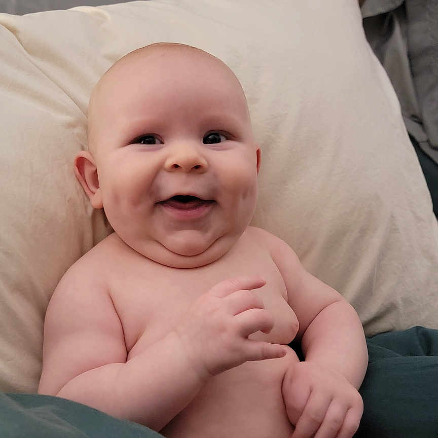 Oakland joined the competition — help win amazing prizes! baby, smiling, diaper, blanket, pillow, bed, wood_paneling, happy, infant, skin, chubby, sitting, indoors, comfortable, cute, child, portrait, relaxed, young, person