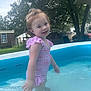 child, toddler, swimsuit, pool, water, outdoor, backyard, trees, grass, play, summer, smile, happy, ripple, daylight, nature, fun, person, pink, blue