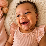 Aulani joined the competition — help win amazing prizes! baby, smiling, pink_dress, curly_hair, face, child, blanket, flowers, happy, portrait, infant, cute, skin, person, indoors, closeup, soft_light, cozy, toddler, natural