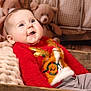 baby, child, smiling, red_sweater, reindeer_design, wooden_crate, blanket, teddy_bear, blue_eyes, happy, indoor, cozy, portrait, holiday, cute, soft_toys, knitwear, infant, warm, relaxed