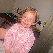 Mya participe au concours pour gagner de l'argent avec cette photo : child, toddler, girl, smiling, portrait, indoor, pink_sweatshirt, barbie_print, pajamas, wet_hair, red_eye, hairbrush, sitting, hands, table, curtain, door, floor, happy, bedroom