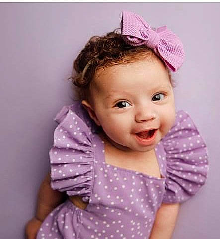 Oakley is registered to the contest to win money with this photo: arm, baby_toddler_clothing, cheek, chin, eyebrow, eyelash, face, happy, head, magenta, neck, outerwear, person, pink, purple, skin, sleeve, smile, textile, toddler