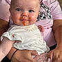 baby, blue_eyes, child, close_up, curious_look, cute, face, hands, holding, indoor, infant, mealtime, messy_face, nail_polish, orange_sauce, patterned_pants, person, pink_shirt, skin, white_dress