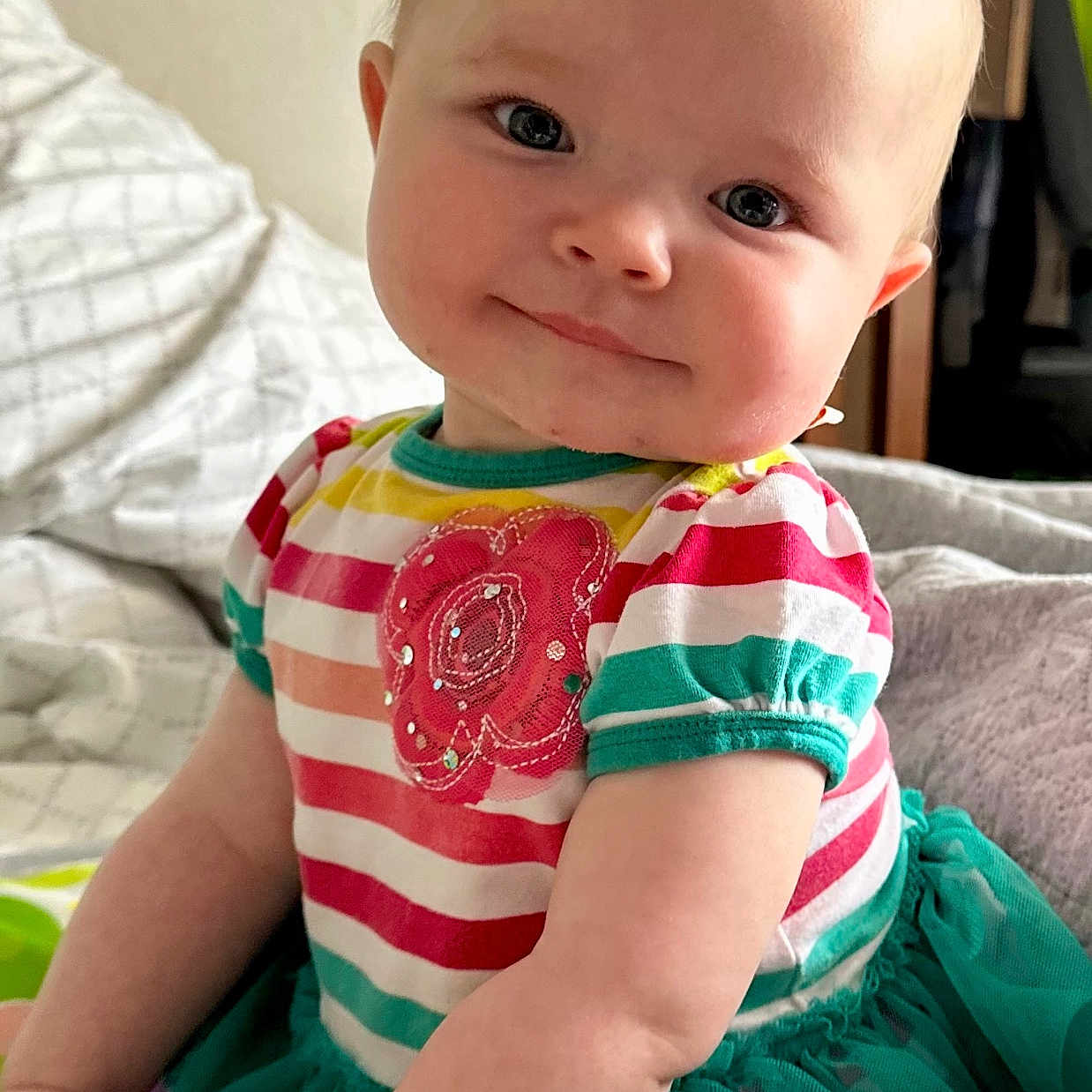 Berklee joined the competition — help win amazing prizes! baby, bed, blanket, child, clothing, cute, face, flower_applique, happy, head, indoor, infant, person, pillow, portrait, sitting, skin, smiling, striped_clothing, toddler