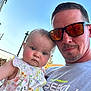 Berklee joined the competition — help win amazing prizes! adult, baby, casual_wear, child, clothing, cute, daylight, expression, facial_hair, family, floral_dress, holding, man, outdoor, parent, person, portrait, reflection, sky, sunglasses
