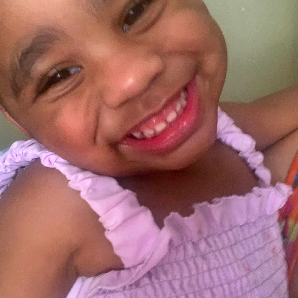 Asie is registered to the contest to win money with this photo: cheeks, child, closeup, cute, emotion, expression, eyebrows, face, happy, human, indoor, innocence, joy, person, portrait, purple_dress, skin, smile, teeth, young