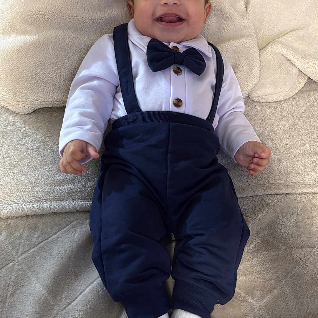 Yumel is registered to the contest to win money with this photo: baby, blanket, bow_tie, child, clothing, couch, cute, face, feet, hands, happy, indoor, infant, lying_down, pants, portrait, smiling, socks, suspenders, white_shirt