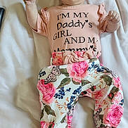 Makaylla joined the competition — help win amazing prizes! baby, child, infant, bed, bedding, headband, floral, pants, shirt, text, person, lying_down, cute, pink, flower, pattern, open_mouth, indoors, fabric, sleepwear