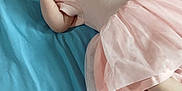 Makaylla is registered to the contest to win money with this photo: baby, infant, pink_dress, blue_bedspread, bed, lying_down, curious, finger_near_mouth, soft_fabric, indoor, child, person, young, cute, small, toddler, blanket, colorful, head, face