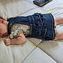 baby, sleeping, denim_dress, floral_shirt, socks, bottle, cushion, pillow, indoor, infant, resting, cute, peaceful, child, person, soft_lighting, bed, home, newborn, relaxation