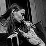 woman, dog, kiss, affection, small_dog, black_and_white, portrait, outdoor, love, pet, closeup, cuddle, face, long_hair, happy, animal, cute, interaction, furniture, cushion