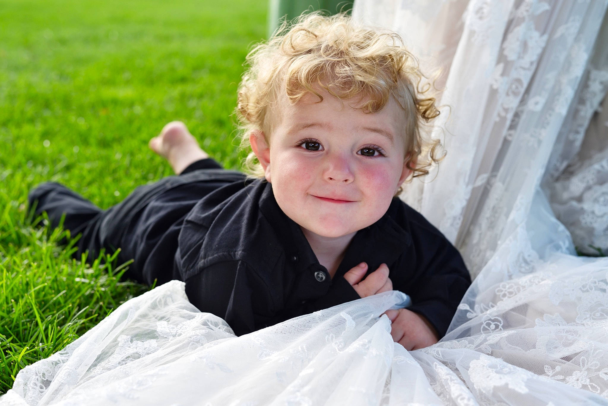 Jaxon is registered to the contest to win money with this photo: baby, blond, child, dress, event, eye, flash_photography, formal_wear, fun, grass, happy, iris, joy, leisure, people_in_nature, person, plant, sitting, smile, toddler