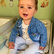 Zeus is registered to the contest to win money with this photo: baby, barefoot, casual_clothing, changing_table, child, cushion, cute, denim_jacket, fox, giraffe, hair_spikes, happy, indoors, nursery, pants, penguin, person, smiling, toddler, wall_decals