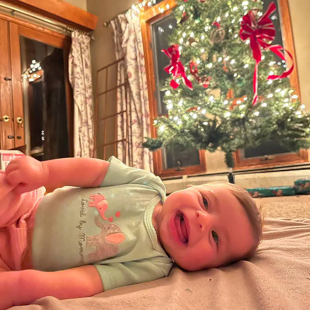 Hayley joined the competition — help win amazing prizes! baby, child, christmas, christmas_decoration, christmas_ornament, christmas_tree, comfort, door, event, flooring, happy, holiday, human_body, ornament, person, plant, room, smile, toddler, tree
