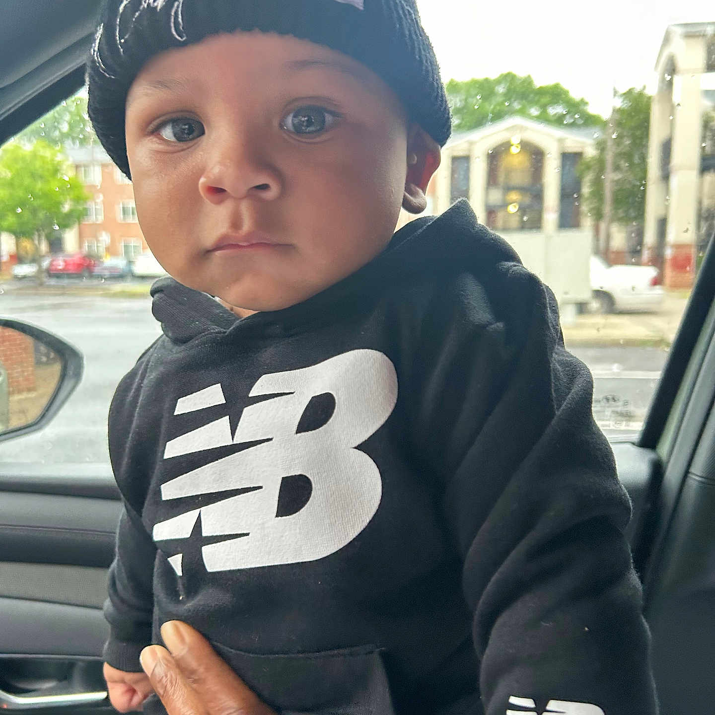 Jaheim joined the competition — help win amazing prizes! toddler, child, baby, black_clothing, hoodie, knit_hat, new_balance_logo, hand, car_interior, window, rain, urban, building, person, face, eyes, portrait, expression, support, casual