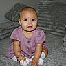 baby, child, purple_dress, socks, couch, cushion, indoor, smiling, cute, plush, furniture, person, portrait, seated, looking_at_camera, cozy, home, soft_texture, infant, adorable