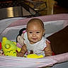 Lucia is registered to the contest to win money with this photo: baby, playpen, plush_toy, pikachu, minnie_mouse, pillow, smile, child, indoor, happy, cute, person, toy, infant, seated, clothing, mesh, pink, yellow, brown