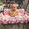 baby, shopping_cart, pink_cushion, polka_dot, warehouse, store, aisle, paper_products, smiling, child, infant, barefoot, happy, face, cute, retail, cart, floor, clothing, person