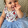 baby, child, smiling, blue_tutu, cute, sitting, thumb_in_mouth, colorful, rainbow_background, patterned_clothing, curly_hair, face, indoors, cushion, happy, portrait, playful, infant, apparel, person