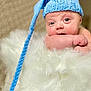 baby, infant, blue_hat, knit_hat, braided_string, fluffy_blanket, white_fur, cute, portrait, closeup, child, soft_texture, pink_cheeks, wide_eyes, resting, cozy, indoors, peaceful, adorable, newborn