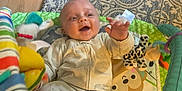 Christopher joined the competition — help win amazing prizes! baby, infant, smiling, onesie, play_mat, toy, plush_toy, happy, lying_down, child, floor, carpet, hand, face, cute, indoor, colorful, striped, pattern, young_child