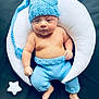 baby, infant, knitted_hat, knitted_pants, blue_clothing, crescent_moon_pillow, white_pillow, star_cushions, soft_toys, black_background, child, cute, portrait, laying_down, bare_chest, indoors, cozy, newborn, baby_fashion, sleepy