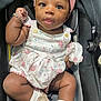 baby, infant, girl, car_seat, headband, bracelet, dress, floral_pattern, footwear, socks, cute, child, portrait, indoor, person, smile, skin, face, eyes, hands