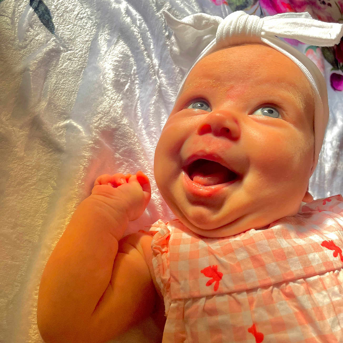 Layla is registered to the contest to win money with this photo: baby, bodypart, bonnet, clothing, dress, face, finger, furniture, hand, happy, hat, head, mouth, newborn, person, photography, portrait, quilt, smile, teeth