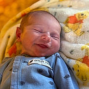Luca is registered to the contest to win money with this photo: baby, blanket, blue_clothing, cartoon_bears, child, cozy, cute, face, happy, head, indoors, infant, newborn, peaceful, portrait, resting, sleeping, smile, soft_texture, warm_light