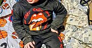 Donnavee joined the competition — help win amazing prizes! basketball_pattern, beanie, bed, blanket, boots, child, clothing, curly_hair, face, football_pattern, hands, hat, hoodie, indoor, rolling_stones_logo, sitting, sports_bedspread, sweatpants, toddler, tongue_logo