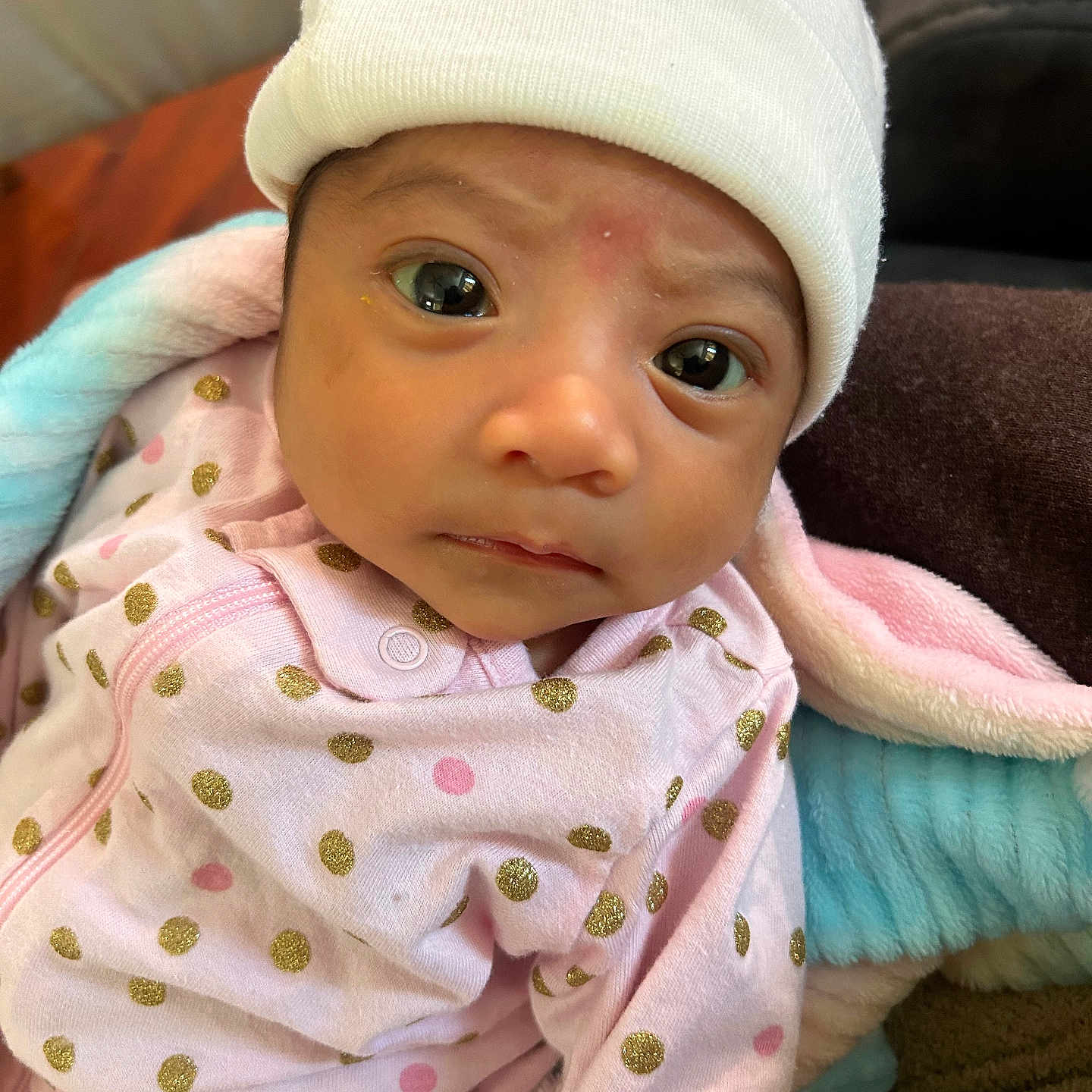 Gia S is registered to the contest to win money with this photo: apparel, baby, blanket, child, closeup, cozy, curious_expression, cute, face, hat, headwear, indoor, infant, newborn, person, pink_clothing, polka_dots, sleepwear, soft_texture, young