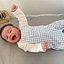 baby, infant, two_months, happy, smiling, blue_outfit, white_sleeves, lying_down, raised_arm, wooden_sign, milestone, crib, soft_surface, cute, newborn, portrait, child, clothing, celebration, face