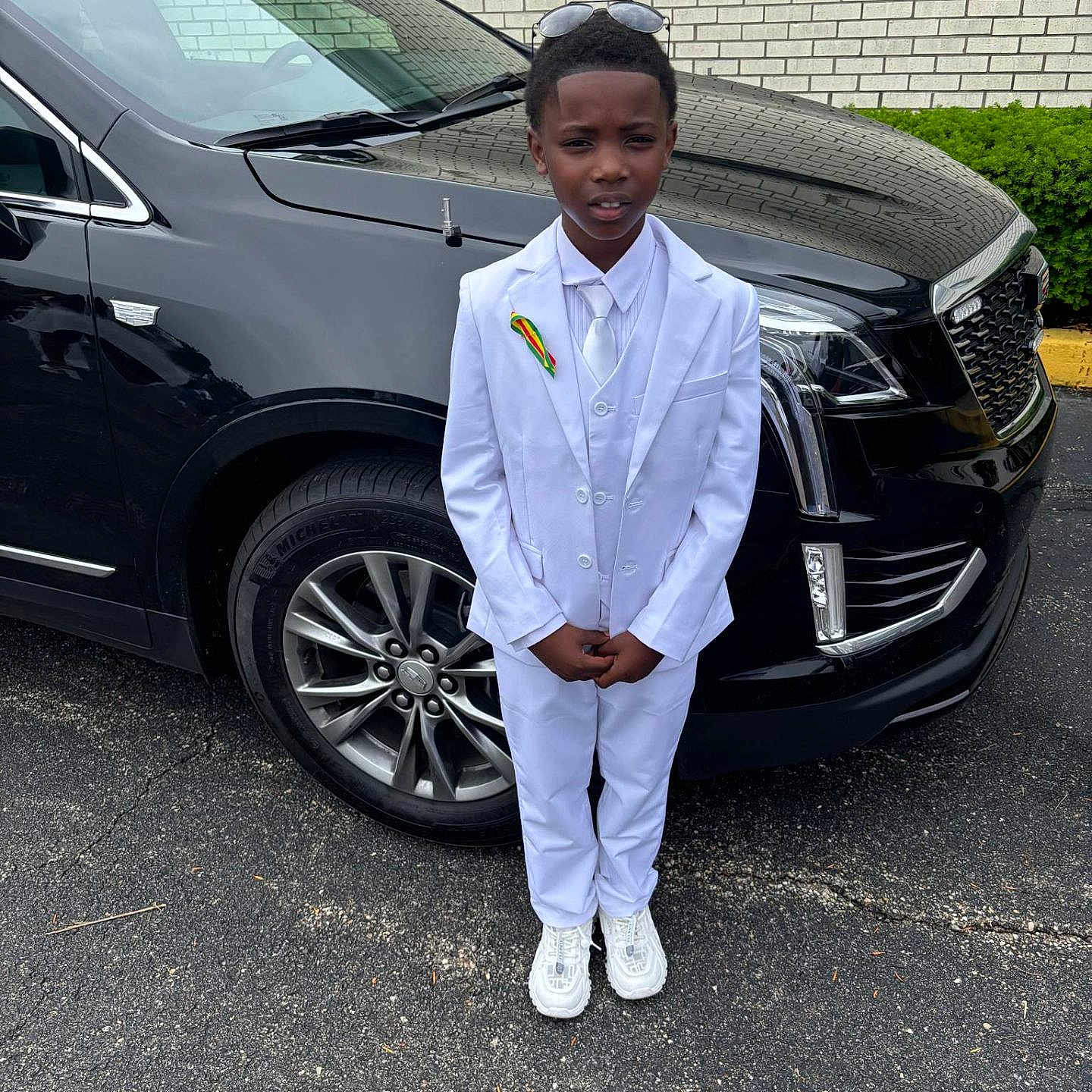 Antwon joined the competition — help win amazing prizes! black_suv, boy, car, child, formal_wear, headwear, outdoor, parking_lot, pavement, person, portrait, ribbon, shoes, standing, sunglasses, tie, tire, urban, vehicle, white_suit