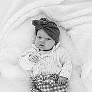Agathe participe au concours pour gagner de l'argent avec cette photo : baby, infant, headwrap, knitted_sweater, checkered_pants, blanket, soft_texture, cozy, cute, portrait, newborn, child, hands, face, lying_down, monochrome, black_and_white, warmth, expression, indoors