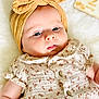 baby, infant, headband, yellow_headband, bow, dress, floral_pattern, buttoned_dress, soft_blanket, wooden_block, number_two, milestone, portrait, closeup, cute, child, skin, face, lying_down, adorable