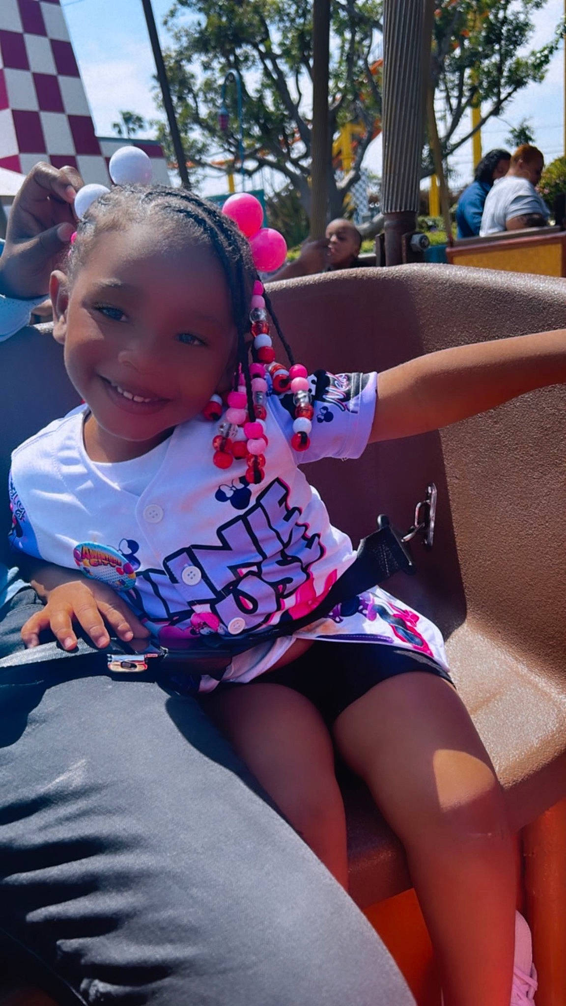 Kamiah is registered to the contest to win money with this photo: child, cool, event, eyewear, fun, grass, happy, human_leg, joy, leisure, magenta, person, pink, recreation, sitting, skin, smile, t_shirt, thigh, toddler